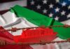 A red cargo ship on a background of Iranian and American flags with barbed wire