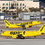 Two yellow Spirit Airlines planes on airport taxiway.