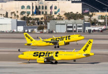 Two yellow Spirit Airlines planes on airport taxiway.