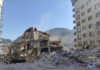 Collapsed building surrounded by debris and mountains