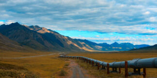 A long pipeline running through a mountainous landscape under a cloudy sky