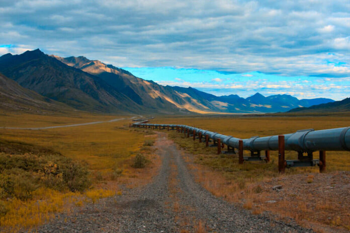 726390229 A long pipeline running through a mountainous landscape under a cloudy sky