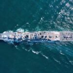 Aerial view of a naval ship navigating through the ocean