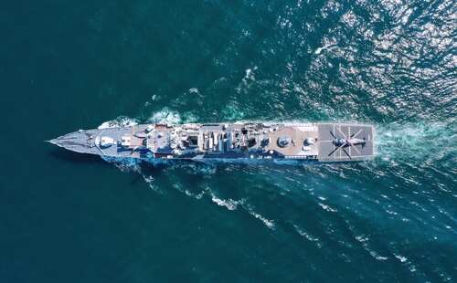 Aerial view of a naval ship navigating through the ocean