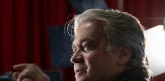 Man with gray hair speaking at an indoor event with dramatic lighting