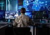 Military personnel monitoring multiple screens in a command center