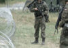 Soldiers standing near barbed wire fence outdoors grassy