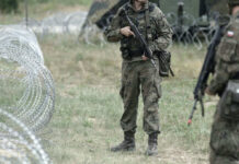 Soldiers standing near barbed wire fence outdoors grassy