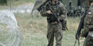 Soldiers standing near barbed wire fence outdoors grassy