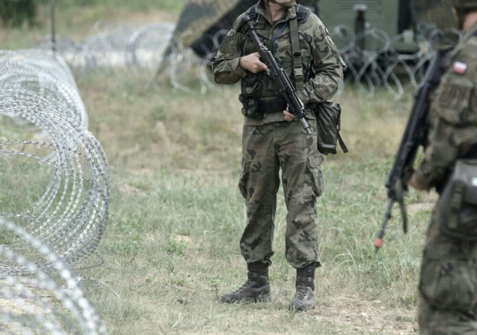Soldiers standing near barbed wire fence outdoors grassy