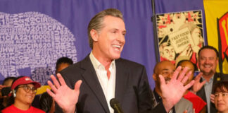Man speaking at podium surrounded by smiling people.