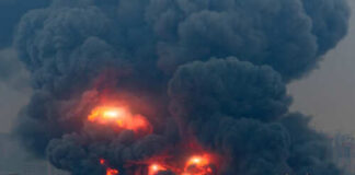 Large industrial fire with thick black smoke and flames