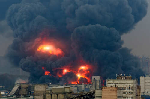 Powerful,Explosion,With,Bright,Flashes,And,Black,Smoke,In,The Large industrial fire with thick black smoke and flames