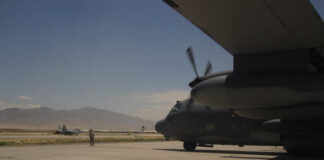 Military aircraft on an airfield with a crew member in the foreground