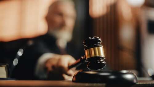 A judge holding a gavel in a courtroom setting