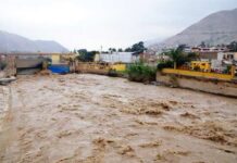 Shocking Mid-Air Crash: Oliver Tree Dies A flooded river flowing through an urban area with buildings in the background