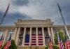 Historic building with large American flag and multiple flags in front
