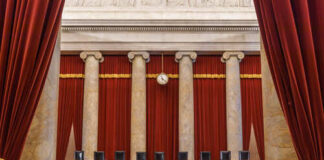 Interior view of a courtroom with red curtains and marble columns