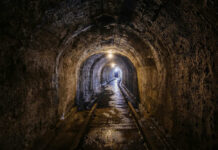 Cartel Tunnel Lurks Under El Paso A dimly lit underground tunnel with wet stone walls and railway tracks