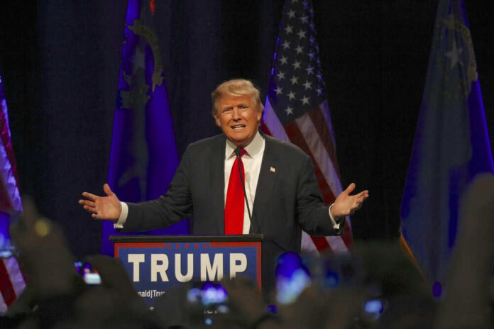 353116961-1 Man speaking at a podium with American flags.