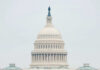 The U.S. Capitol building adorned with flags during a national event with a large crowd in front