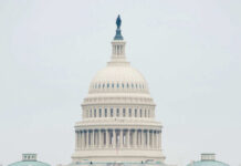 The U.S. Capitol building adorned with flags during a national event with a large crowd in front
