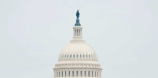 The U.S. Capitol building adorned with flags during a national event with a large crowd in front