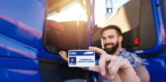 Man holding a commercial driver's license in front of a blue truck