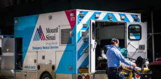 A healthcare worker pushing a stretcher next to an ambulance