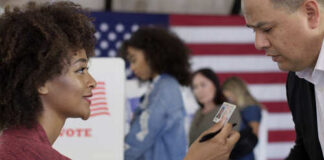 A woman showing her ID to a man at a voting station