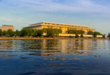 Modern building reflecting on water during sunset