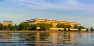 Modern building reflecting on water during sunset