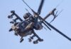 Trump’s Iran Blitz Leaves One Chilling Question An Apache helicopter flying in the sky with visible rotor blades