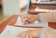 DMV Crackdown Blindside A student's hand holding a pencil while writing on a sheet of paper