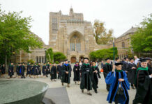 Graduates and faculty in academic regalia walking on a university campus