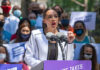 Person speaking at a public event with crowd.