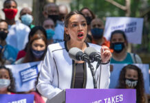 Person speaking at a public event with crowd.