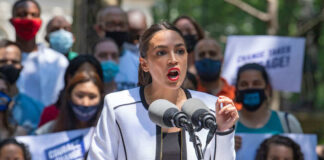 Person speaking at a public event with crowd.