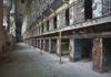 Interior view of an abandoned prison with empty cells and peeling paint