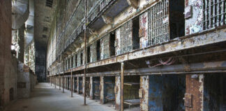 Interior view of an abandoned prison with empty cells and peeling paint