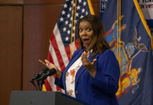 Person speaking with surprised expression at podium flags behind