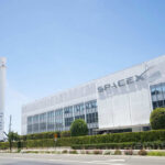 SpaceX’s Stock: Going to The Moon $$$ SpaceX building with rocket and palm tree outside