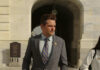 Power-and-Privilege Love Story Explodes Man in suit walking outside stone building
