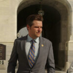 Man in suit walking outside stone building