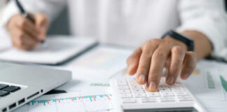 A person using a calculator while taking notes in a business setting