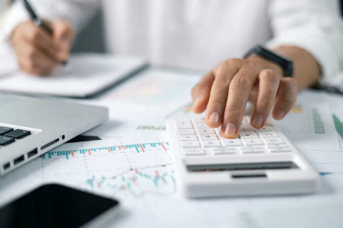 2441922909 A person using a calculator while taking notes in a business setting