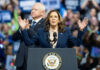 Woman speaking at podium, man standing behind.