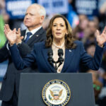 Surprise Check On Hunter’s Hottest Charge Woman speaking at podium, man standing behind.