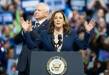 Surprise Check On Hunter’s Hottest Charge Woman speaking at podium, man standing behind.