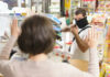 A masked individual threatening a store clerk during a robbery